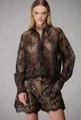 Camisa negra de encaje semitransparente con diseño floral, cuello camisero y mangas largas.