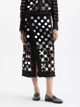 Pollera cruzada de largo midi, confeccionada en guipur negro con espejos circulares bordados. Presenta un lazo de ajuste en la cintura y forrería interna al tono.