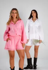 Conjunto de dos piezas confeccionado en lino color blanco. Incluye una camisa de corte holgado con mangas abullonadas y bolsillos frontales, y un short de tiro alto con cintura elástica y forro interior.