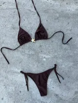 Conjunto de bikini color crema con corpiño triangular con detalle de estrella dorada y bombacha con tiras laterales.