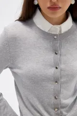 Saco de punto al cuerpo, color negro, con cuello redondo, manga larga y cierre frontal con botones pequeños.