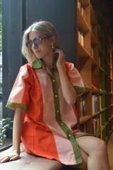 Camisola corta con cuello camisero, abotonada al frente, con mangas cortas y diseño color block en naranja, rosa y verde.