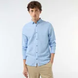 Camisa de manga larga en color azul cielo, confeccionada en mezcla de lino con botones frontales imitación madera y cuello con botones.
