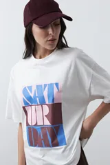 Remera de manga corta con corte boxy fit, color blanco, con estampa frontal geométrica en tonos azul, rosado y marrón.