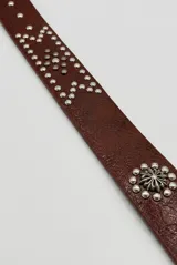 Cinto de cuero sintético marrón camel, con tachas metálicas plateadas decorativas y hebilla de metal envejecido.