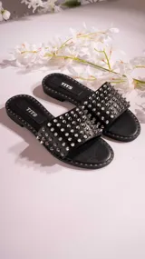 Sandalias chatas negras con tira ancha sobre el empeine, cubierta de tachas plateadas.