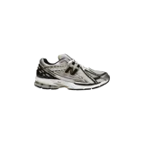 Championes New Balance modelo 1906R, color blanco con detalles metalizados en plateado, negro y dorado. Confeccionados en malla técnica y material sintético, cuentan con el característico logo "N" en el lateral y entresuela con tecnología N-ergy.