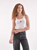 Musculosa corta de tejido acanalado color verde menta, con escote redondo y tirantes anchos. Presenta un pequeño bordado frontal con forma de flor o mariposa en tonos rosados.