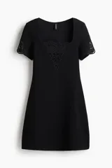 Vestido corto negro en punto interlock pesado, con escote cuadrado pronunciado, mangas cortas y inserciones bordadas en el busto y los puños.