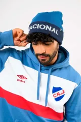 Gorro beanie de lana Umbro, color azul marino con franja oscura y la inscripción "NACIONAL" en letras blancas bordadas.