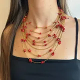 Collar de múltiples vueltas con tubitos dorados y cuentas de coral rojo.