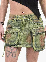 Minifalda de jean con efecto batik en tonos verde y marrón, de corte ajustado. Presenta un diseño tipo cargo con dos bolsillos pequeños superiores y dos bolsillos grandes laterales con solapa.