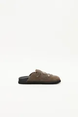 Zueco de cuero descarne negro con diseño de estilo western, decorado con tachas metálicas plateadas y una hebilla lateral ajustable.