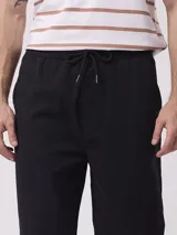 Pantalón negro de corte recto con cintura elástica tipo jogger y bolsillos laterales, confeccionado en mezcla de algodón y elastano.