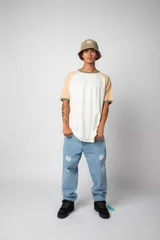 Remera estilo raglán color blanco en el cuerpo, con mangas en tono tostado y ribetes en color verde militar en el cuello y los puños.