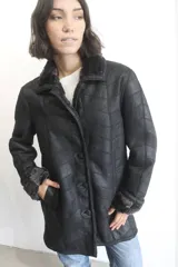 Campera de napalán de cuero genuino en color negro, con diseño de paneles horizontales y forro interior de piel sintética visible en cuello y puños. Cuenta con cierre frontal de botones.