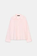 Camisa de popelín color rosa pálido, con cuello solapa, escote pico y manga larga terminada en puño. Cierre frontal con botones.