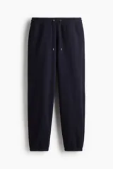 Pantalón deportivo de felpa azul marino con cintura elástica y cordón ajustable, bolsillos laterales y puños acanalados en los tobillos.