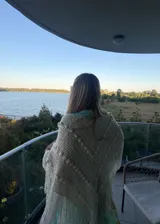 Ruana tejida artesanalmente en color crudo, con diseño triangular, textura de puntos en relieve y terminación con flecos largos en todo el borde.