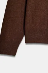 Jersey de punto liso color verde, con cuello redondo y manga larga. Confeccionado en hilatura de lana 100% con tacto suave.