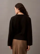 Sweater negro de punto de algodón con escote en V, puños, cuello y dobladillo con punto canalé.