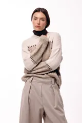 Sweater de tejido de punto grueso con diseño de bloques de color en tonos beige, marrón y bordó. Presenta un corte relajado, mangas amplias y detalles de costuras visibles en contraste que separan las franjas de color.