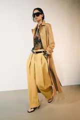 Jeans de tiro bajo y corte wide leg, color amarillo mostaza, con pliegues frontales, bolsillos ocultos y cierre frontal con cremallera, botón y ganchos metálicos.