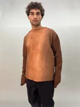 Buzo de lana merino afieltrada color negro con estampado abstracto plateado en el frente. Tiene cuello redondo y puños con forma que cubre levemente la mano. Es más largo en la parte inferior trasera.