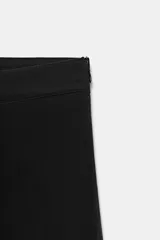 Pantalón capri de tiro medio confeccionado en tejido elástico, con cierre lateral mediante cremallera oculta.
