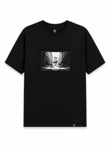 Remera negra de corte clásico con cuello redondo y estampa fotográfica central en blanco y negro que muestra una vista urbana con un puente. Presenta un pequeño logo distintivo en la parte inferior.