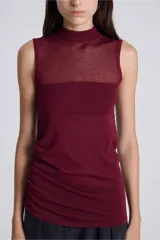 Top sin mangas color bordó, con cuello alto y textura de punto. Presenta un panel superior transparente en el área del pecho y fruncido lateral.
