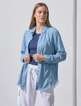 Camisa celeste de tencel, marca Hester & Orchand. Tiene cuello con solapa, escote en V, abertura central con botones, bolsillo aplicado en el frente y ruedo desflecado.