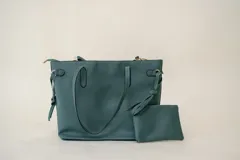 Bolso tipo shopper color verde azulado, con doble asa de mano y correa bandolera desmontable. Incluye un monedero pequeño colgante.