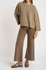 Sweater de lana de corte oversize, con cuello redondo y mangas largas con puños acanalados. Diseño de tejido liso en tono neutro.