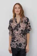 Camisa de corte recto con estampado floral en tonos beige y negro, cuello mao con escote en V y cierre frontal parcial con botones. Presenta mangas tres cuartos con detalle de trabilla para ajustar.