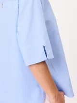 Camisa de manga corta celeste, confeccionada en mezcla de algodón y lino, con cuello camisero y cierre frontal de botones.