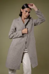 Tapado de corte sastre con diseño de espiga en tonos blanco y negro. Cuenta con solapas clásicas, cierre frontal de un botón y bolsillos laterales.