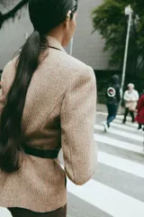 Blazer de corte clásico con cuello solapa y manga larga, confeccionado en tejido con patrón de espiga en tonos tierra y líneas verticales en color salmón. Cuenta con bolsillos delanteros y cierre frontal con botones ocultos.
