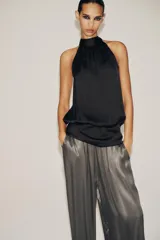 Top negro de tejido satinado con cuello halter y lazada. Cierre lateral con cremallera oculta.