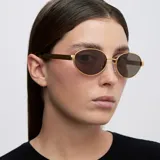 Lentes de sol con montura ovalada de acero inoxidable en color dorado y cristales polarizados en tono marrón. Presentan un diseño de puente fino y patillas con terminación en carey.
