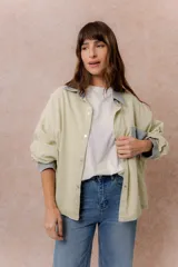 Camisa lila de calce relajado y manga larga, con cuello clásico, puños y bolsillo delantero en denim contrastante. Cierre frontal con broches metálicos.