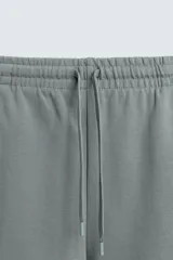 Bermuda de algodón color beige claro, corte relajado (relaxed fit), con cintura elástica ajustable mediante cordón y bolsillos laterales y trasero de plastrón.