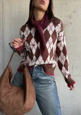 Sweater de tejido de punto con diseño de rombos en tonos chocolate, blanco y detalles en bordó. Presenta cuello redondo, mangas largas y terminaciones acanaladas en puños y ruedo.