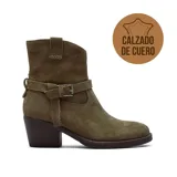 Bota corta de gamuza color marrón, con taco cuadrado y diseño de caña media. Presenta una tira decorativa con hebilla metálica alrededor del tobillo y costuras reforzadas en la parte superior.