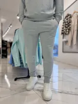 Conjunto de jogging celeste claro compuesto por un canguro con capucha y bolsillo tipo canguro con estampa pequeña del texto "TURK.", y un pantalón de jogging con puños elásticos en los tobillos.