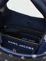 Bolso tipo saco de cuero azul marino con asas superiores. Incluye un pañuelo tipo bandana con estampado paisley blanco que se ata a una de las asas. Viene con un neceser o pouch a juego con estampado de estrellas y corazones.