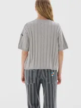 Buzo tejido de manga corta color rojo, con cuello redondo y diseño de punto acanalado y trenzado.