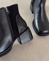 Botines de cuero vacuno en color marrón, con diseño de caña media, taco cuadrado y plataforma delantera. Presentan una combinación de texturas en el cuero y un estilo robusto.