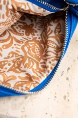 Cartera de mano color arena, con cierre superior y logo de la marca en el frente.