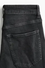 Jean de tiro alto con corte acampanado desde la rodilla, confeccionado en denim con efecto lavado y bajo deshilachado.